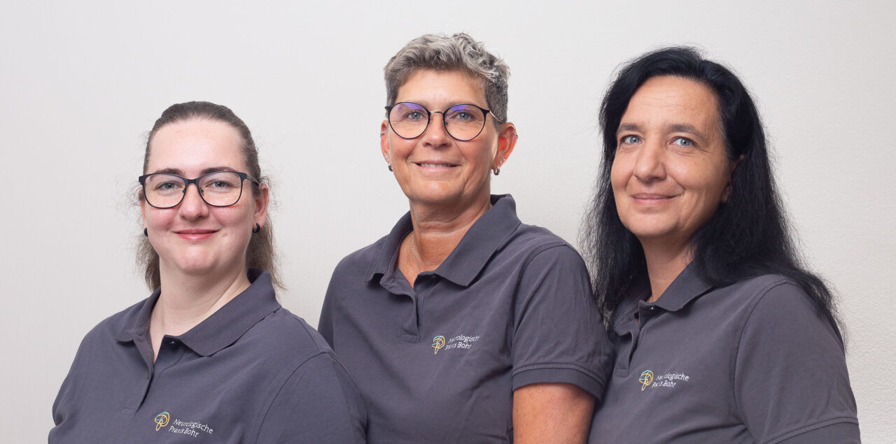 Drei Mitarbeiterinnen in blauen Praxis-Poloshirts